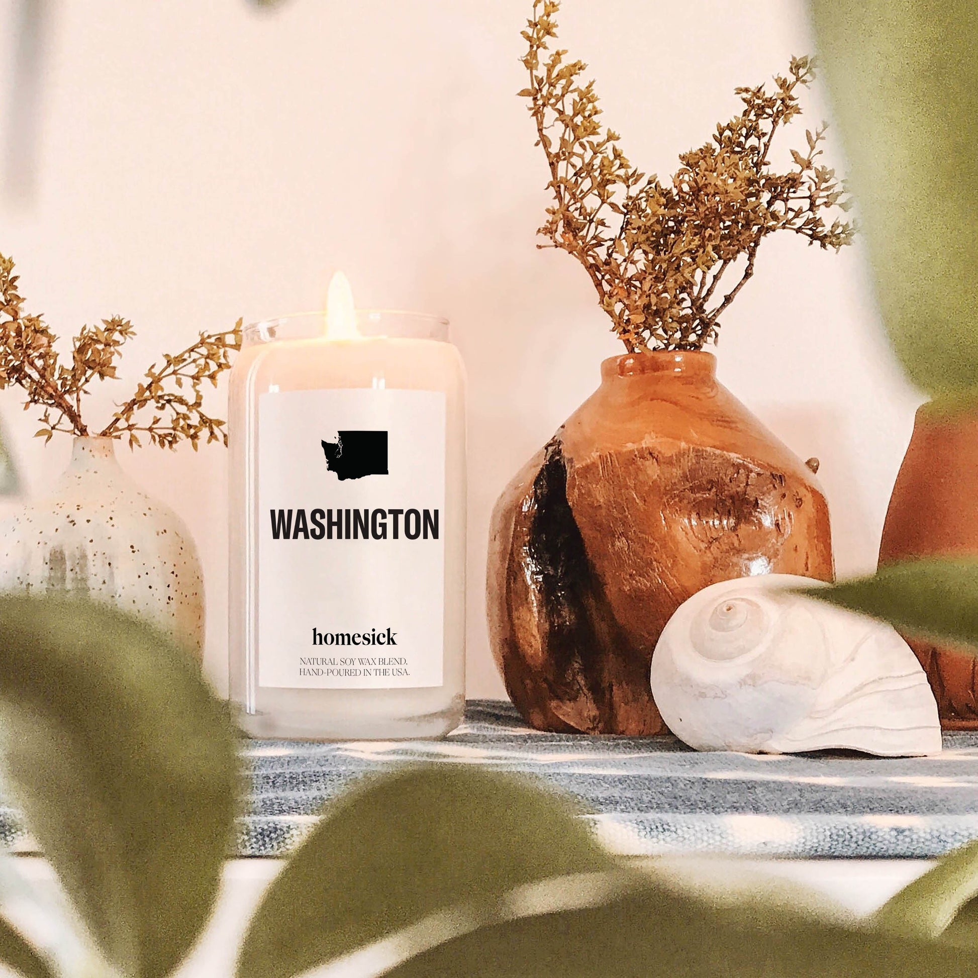 A close up of the Washington candle amongst various greenery home decor items.