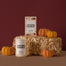 A stylized shot of the Autumn Hayride Candles on a haystack with small pumpkins surrounding the candles.