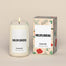 Single Candle next to its packing box that is tan with an overall wildflower print of flowers including the colors red, green and white. 